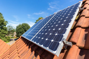 Row of blue solar panels on orange roof.