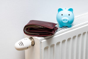 A wallet lying on top of a radiator. There is a small blue piggy bank placed next to it