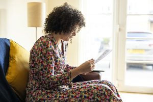 A woman sitting on a sofa, looking at the standing charges on her bill