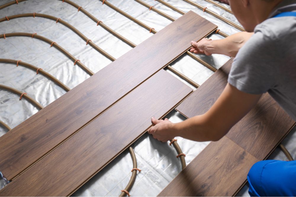 person laying floorboards over underfloor heating