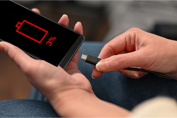 A close up of someone plugging in their phone. The screen shows a low battery symbol with 3% charge
