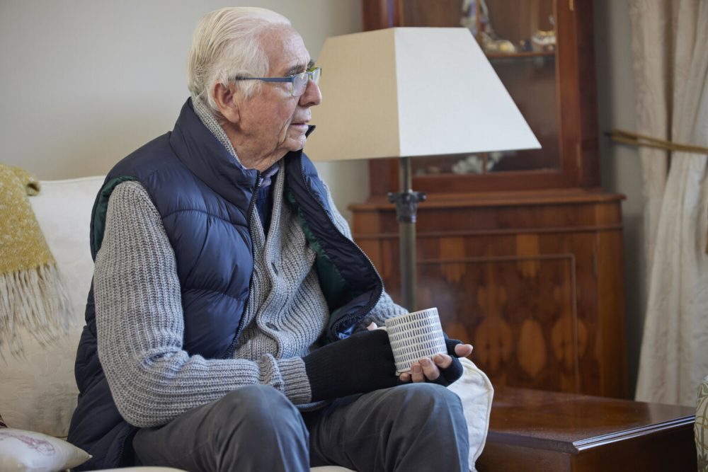 An elderly man sitting on a sofa after a missed appointment with his energy supplier