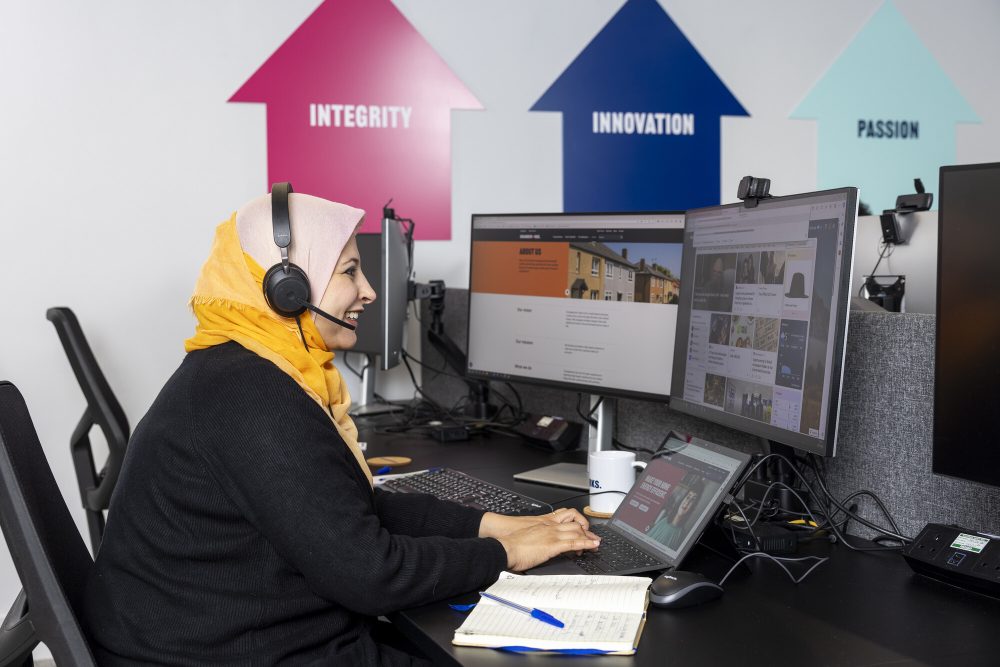 An advisor sits at a computer in the Changeworks office whilst speaking to a customer on the phone.