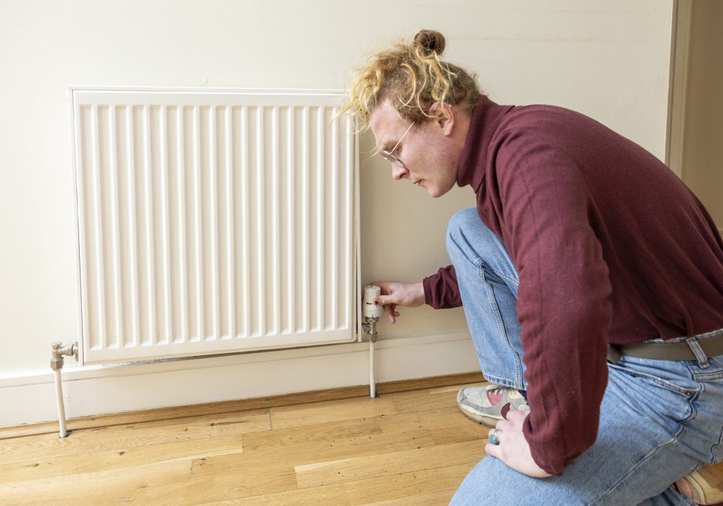 Householder adjusting the Thermostatic Radiator Valve on a radiator